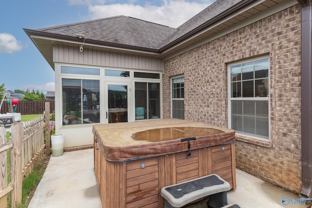 view of patio / terrace with a sunroom, a hot tub, and fence