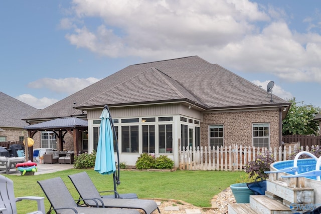 rear view of house with an outdoor living space, a shingled roof, fence, and brick siding
