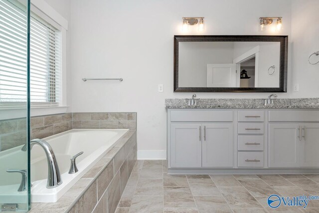 bathroom with tile patterned floors, tiled tub, and vanity