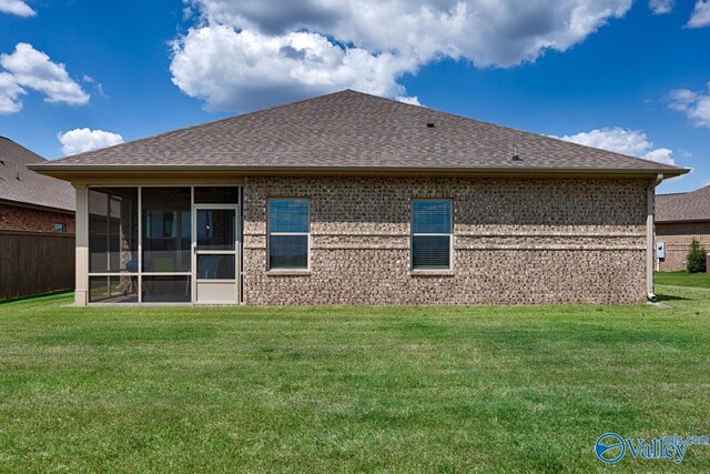 back of property featuring a sunroom and a lawn