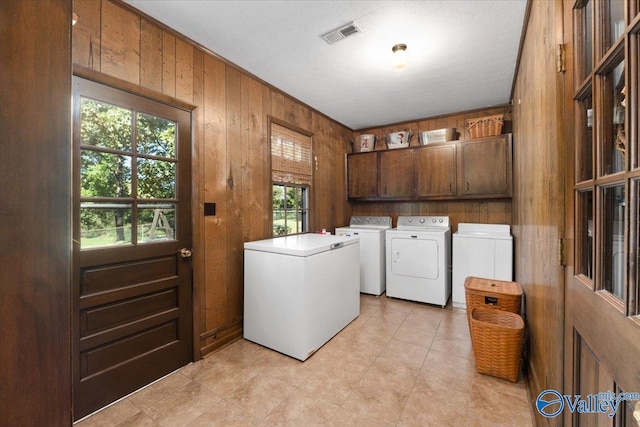 19660 Cox Rd, Athens, AL 35611 - washroom with separate washer and dryer, light tile patterned floors, wood walls, visible vents, and cabinet space