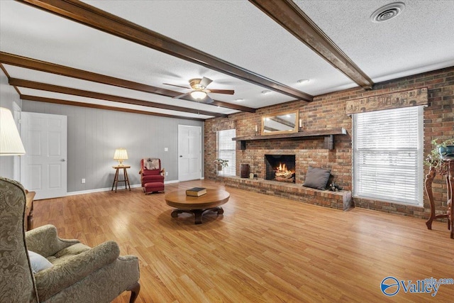 19660 Cox Rd, Athens, AL 35611 - living area featuring brick wall, a fireplace, visible vents, beam ceiling, and wood finished floors