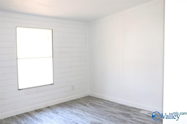 empty room with a textured ceiling, baseboards, and wood finished floors