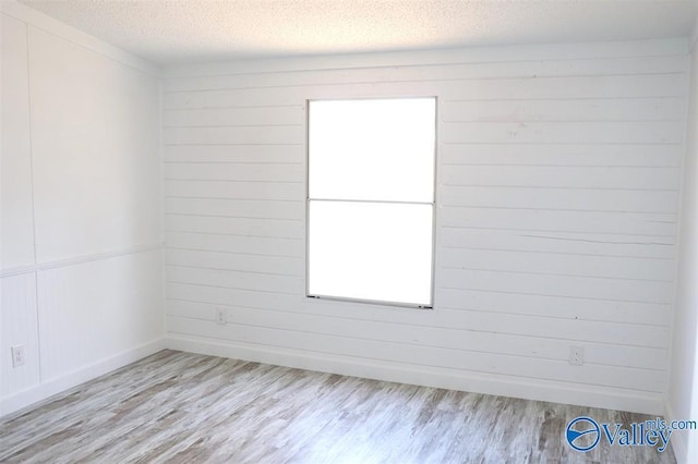 empty room featuring baseboards, a textured ceiling, and wood finished floors