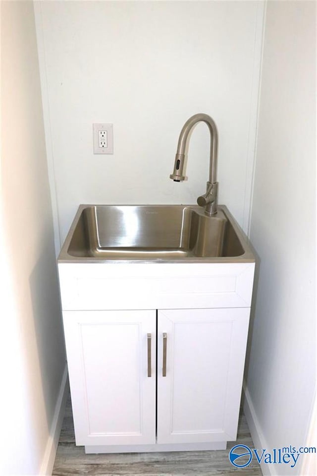 interior details featuring light wood finished floors, white cabinets, and a sink