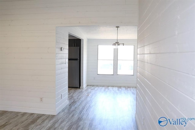 unfurnished dining area with wood walls and wood finished floors