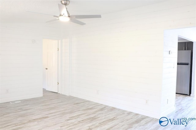 spare room featuring light wood finished floors and a ceiling fan