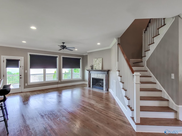 unfurnished living room with hardwood / wood-style flooring, ceiling fan, ornamental molding, and a high end fireplace