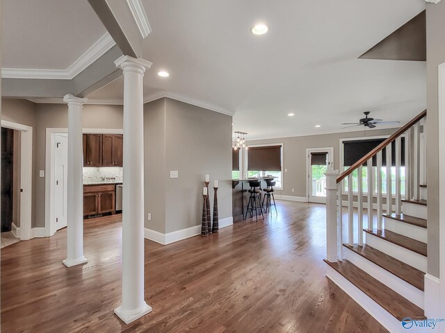 unfurnished living room featuring crown molding, ceiling fan, dark hardwood / wood-style flooring, and decorative columns