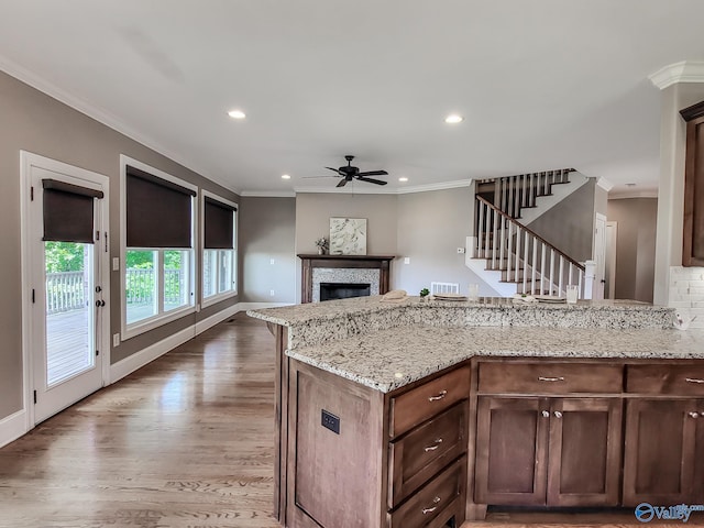 kitchen featuring hardwood / wood-style flooring, crown molding, and light stone counters