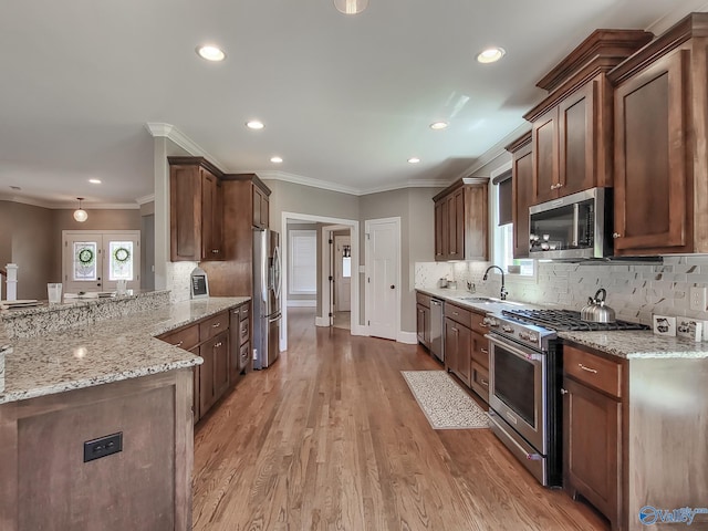 kitchen featuring tasteful backsplash, sink, light stone counters, kitchen peninsula, and stainless steel appliances