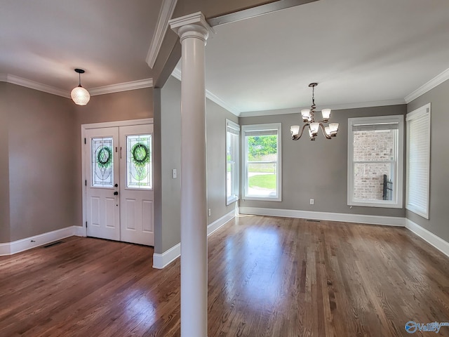 foyer with an inviting chandelier, dark wood-type flooring, ornamental molding, and ornate columns