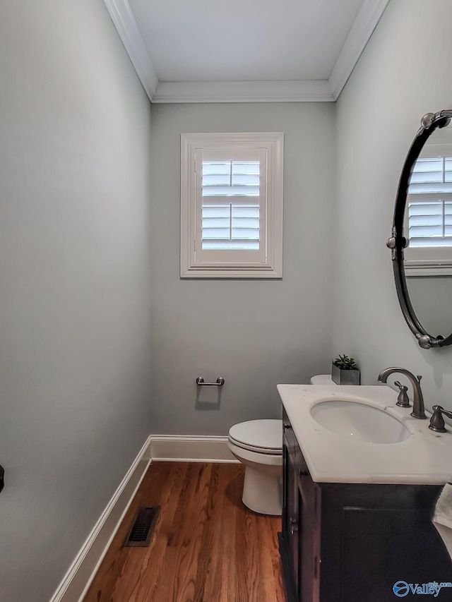 bathroom featuring vanity, wood-type flooring, ornamental molding, and toilet