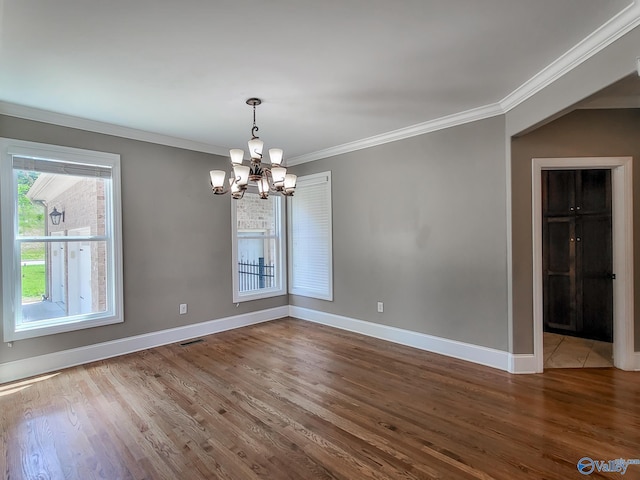 empty room featuring an inviting chandelier, hardwood / wood-style flooring, and ornamental molding