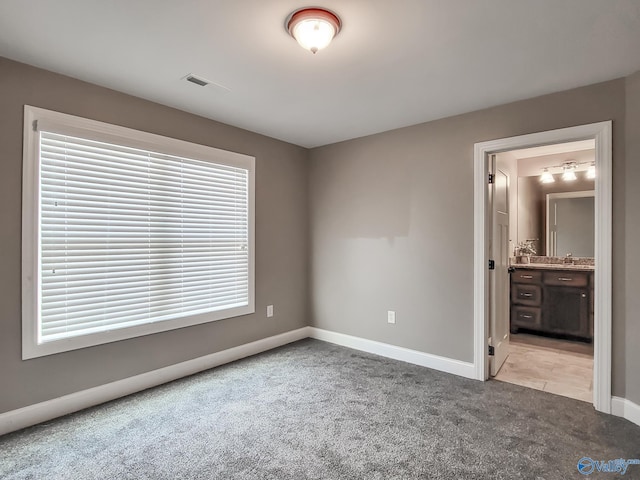 unfurnished bedroom featuring carpet and connected bathroom