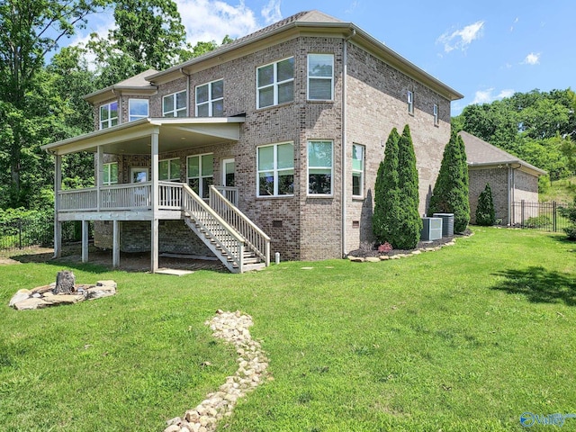 back of property with a wooden deck, a fire pit, a lawn, and cooling unit