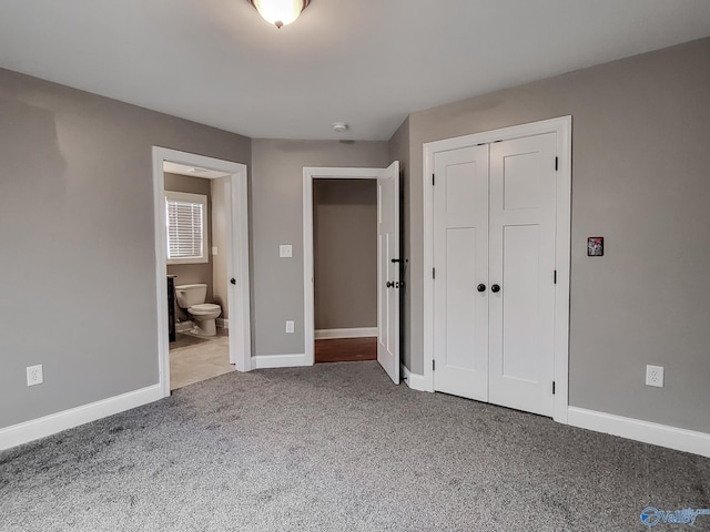 unfurnished bedroom with ensuite bath, carpet floors, and a closet