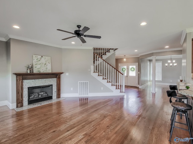 living room featuring hardwood / wood-style flooring, crown molding, and ornate columns