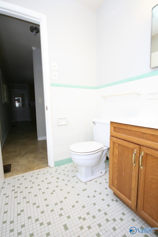 bathroom featuring tile patterned floors, vanity, toilet, and tile walls