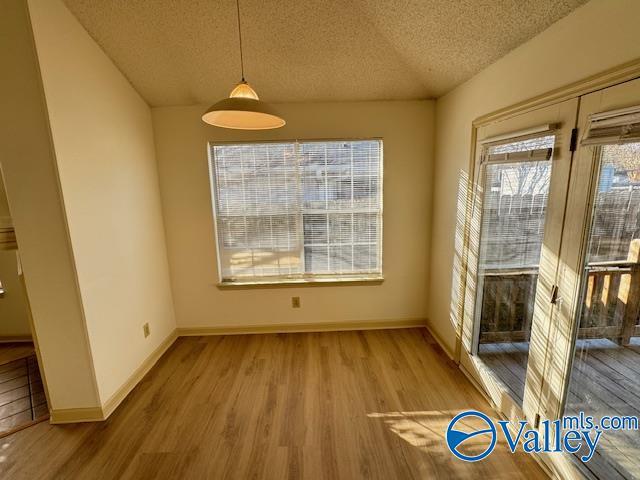 unfurnished dining area with a textured ceiling and light hardwood / wood-style flooring