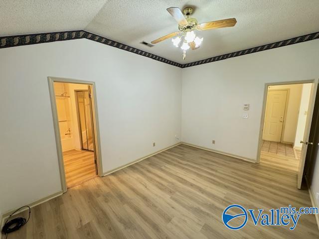 unfurnished bedroom featuring a textured ceiling, ceiling fan, light hardwood / wood-style flooring, and lofted ceiling