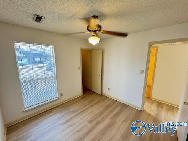 spare room featuring a textured ceiling, light hardwood / wood-style floors, and ceiling fan