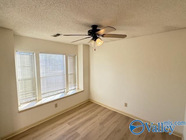 spare room featuring ceiling fan, light wood-type flooring, and a textured ceiling