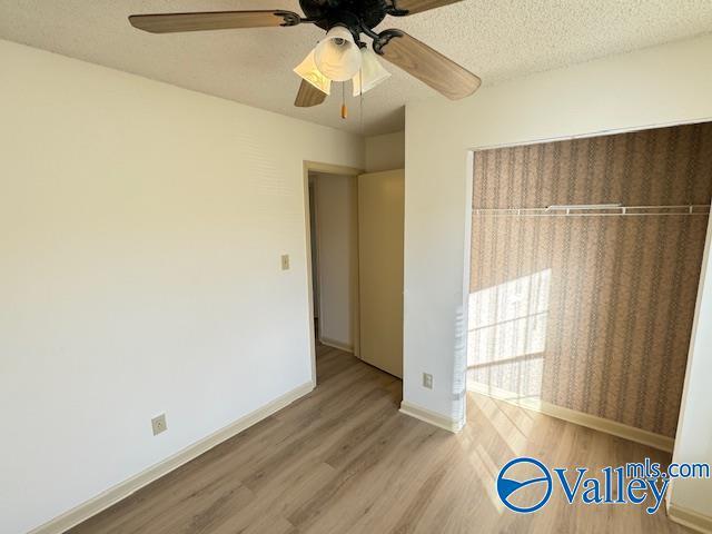 unfurnished bedroom featuring ceiling fan, a closet, a textured ceiling, and hardwood / wood-style flooring