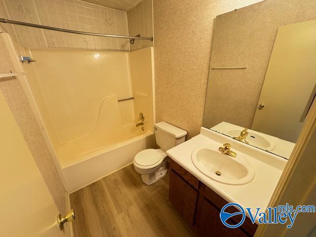 full bathroom featuring hardwood / wood-style floors, vanity, toilet, and tub / shower combination