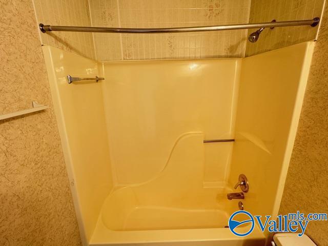 bathroom featuring bathing tub / shower combination and toilet