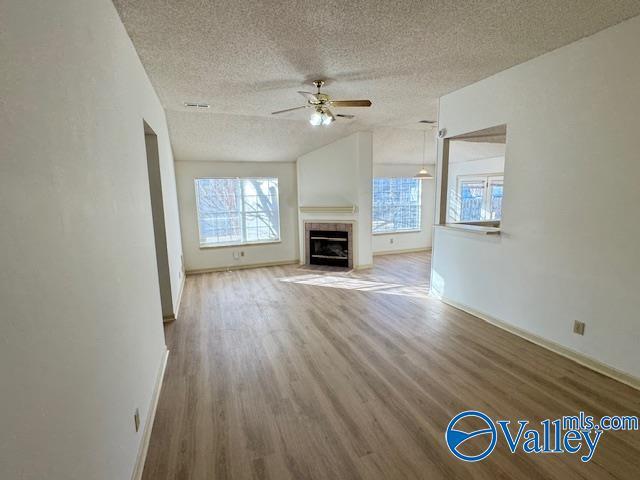 unfurnished living room with ceiling fan, hardwood / wood-style floors, a healthy amount of sunlight, and a textured ceiling