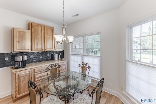 dining room with a notable chandelier, a healthy amount of sunlight, and light hardwood / wood-style flooring