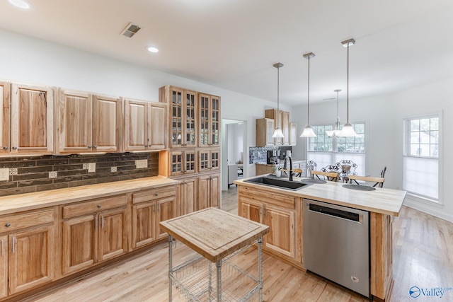 kitchen with a kitchen island with sink, pendant lighting, light hardwood / wood-style flooring, sink, and dishwasher