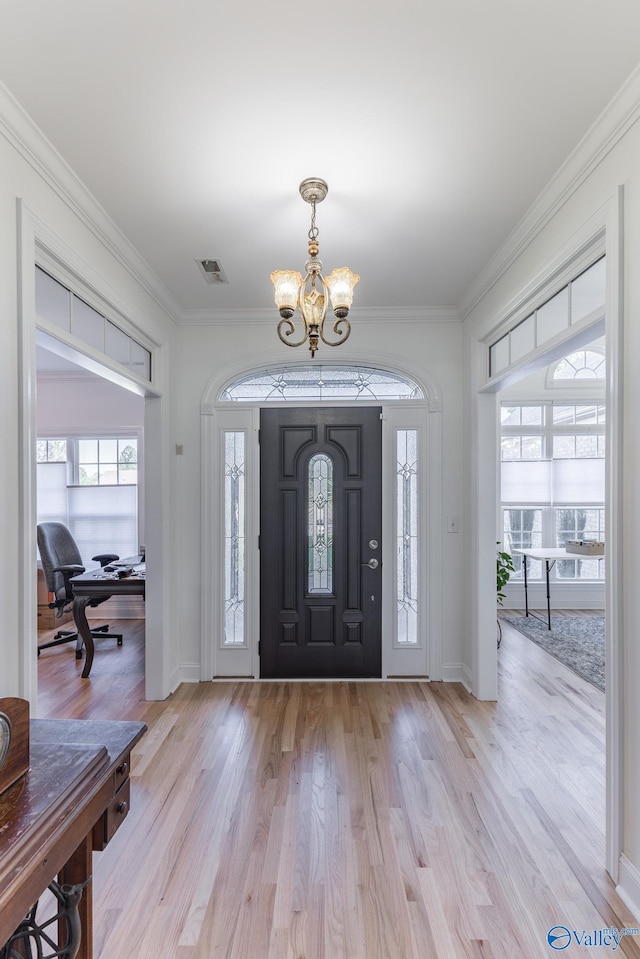 foyer entrance featuring a notable chandelier, crown molding, and light hardwood / wood-style flooring