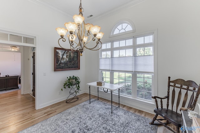 living area with an inviting chandelier, crown molding, hardwood / wood-style flooring, and a healthy amount of sunlight