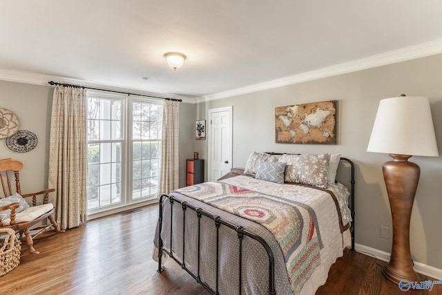 bedroom featuring visible vents, crown molding, baseboards, and wood finished floors