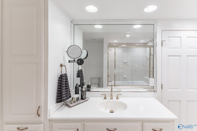 full bathroom with recessed lighting, a shower with door, vanity, and toilet