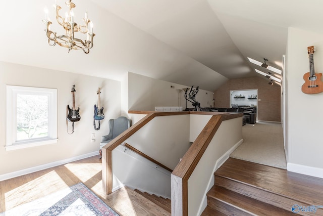 stairway featuring lofted ceiling, baseboards, and wood finished floors