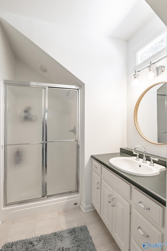 bathroom with lofted ceiling, a stall shower, tile patterned flooring, and vanity