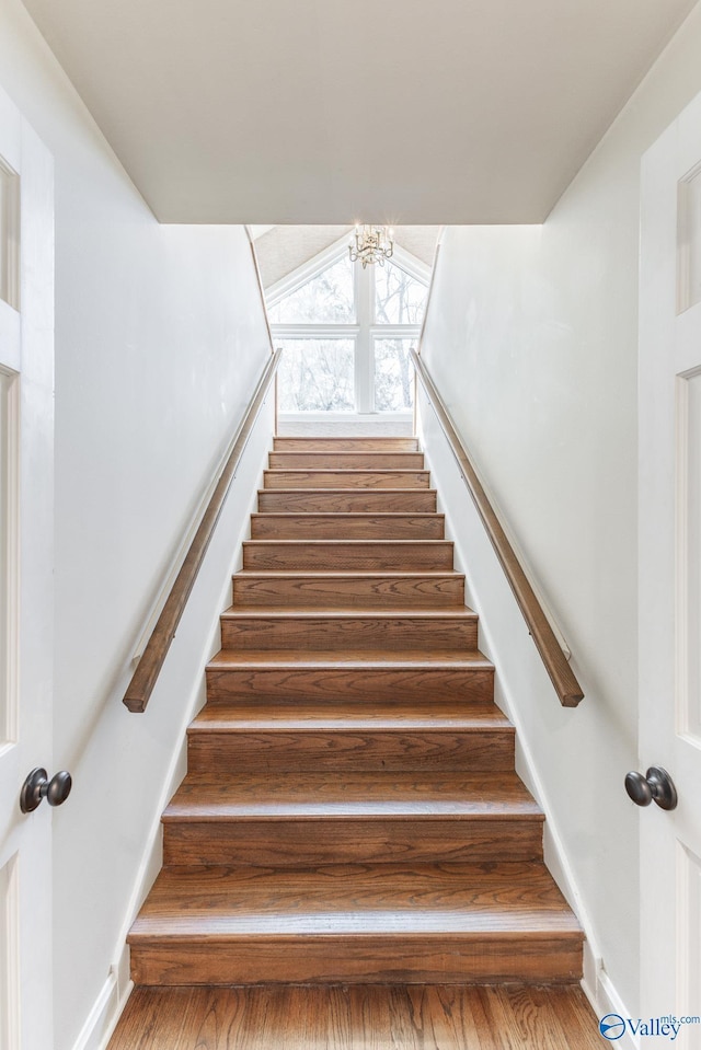 staircase with a notable chandelier