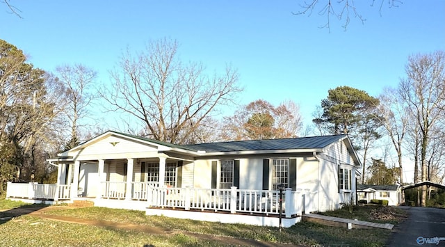 view of front of property with driveway, covered porch, and metal roof