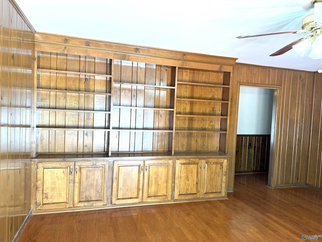 room details with ceiling fan, wood walls, and wood finished floors