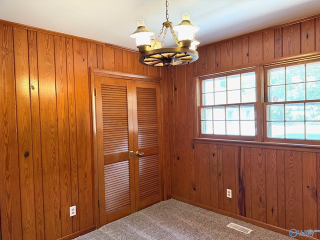 interior space with carpet floors, wood walls, plenty of natural light, and visible vents