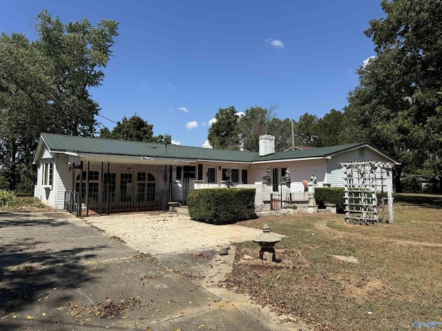 ranch-style home with a porch, metal roof, and a chimney