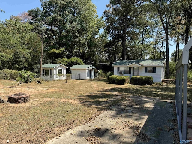 view of front of house featuring an outdoor fire pit, metal roof, a shed, an outdoor structure, and a front lawn