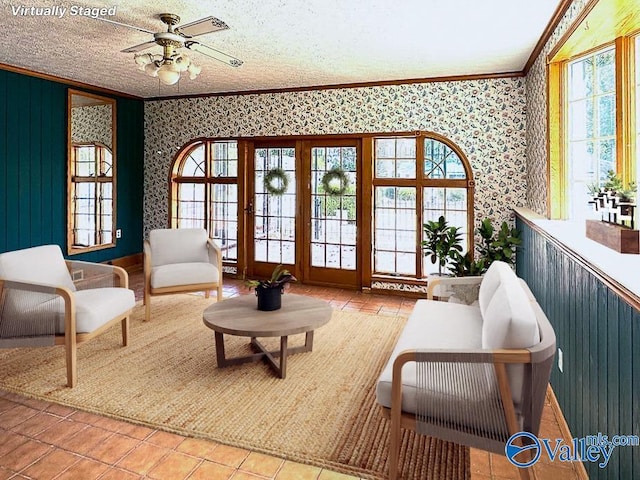 sitting room with a textured ceiling, a ceiling fan, ornamental molding, tile patterned floors, and wallpapered walls