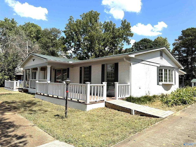 ranch-style home with metal roof, a porch, and a front lawn