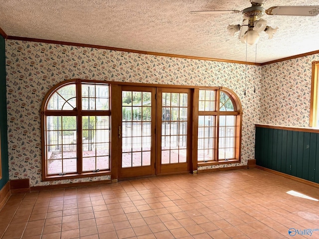 spare room featuring crown molding, ceiling fan, a textured ceiling, tile patterned flooring, and wallpapered walls