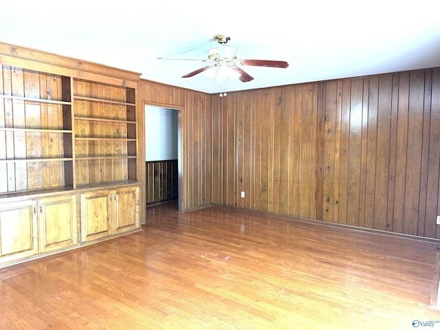unfurnished living room featuring ceiling fan, wood finished floors, and wooden walls