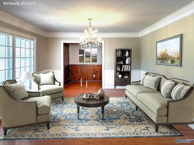 living room featuring a wainscoted wall, crown molding, an inviting chandelier, and wood finished floors